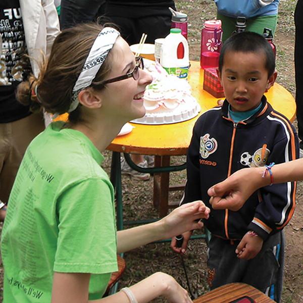 Student making bracelets for children